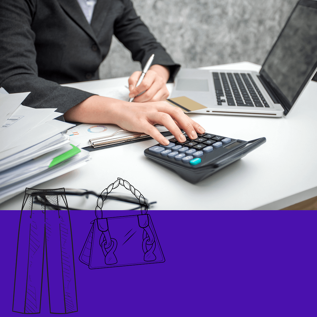 A woman in a gray business jacket works at a computer.
